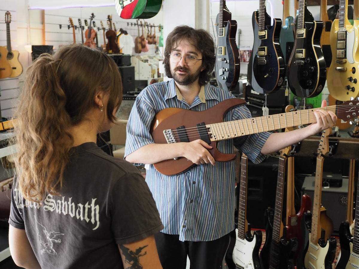 One of our team shows a customer a guitar in the shop.